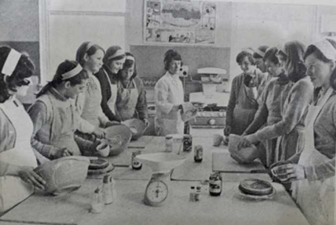 0040  : A group of young ladies being instructed by the Domestic Science teacher Mrs. Eva Brosnan.